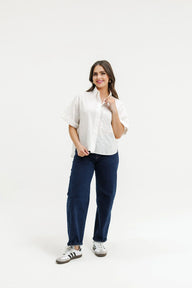 Woman wearing a white blouse and navy pants on a white background