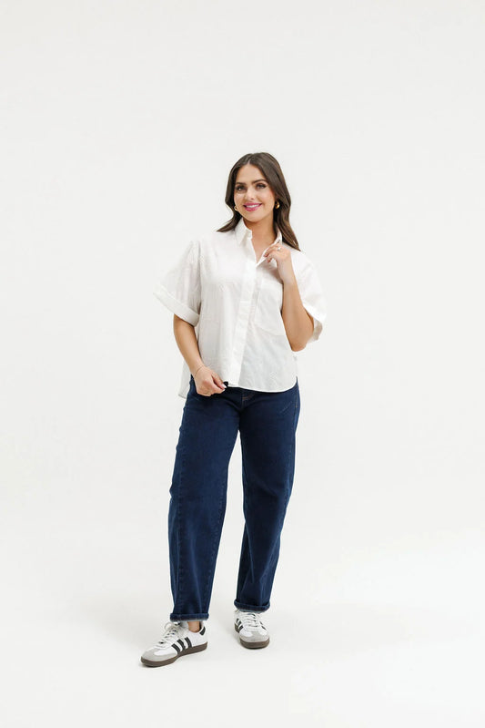 Woman wearing a white blouse and navy pants on a white background