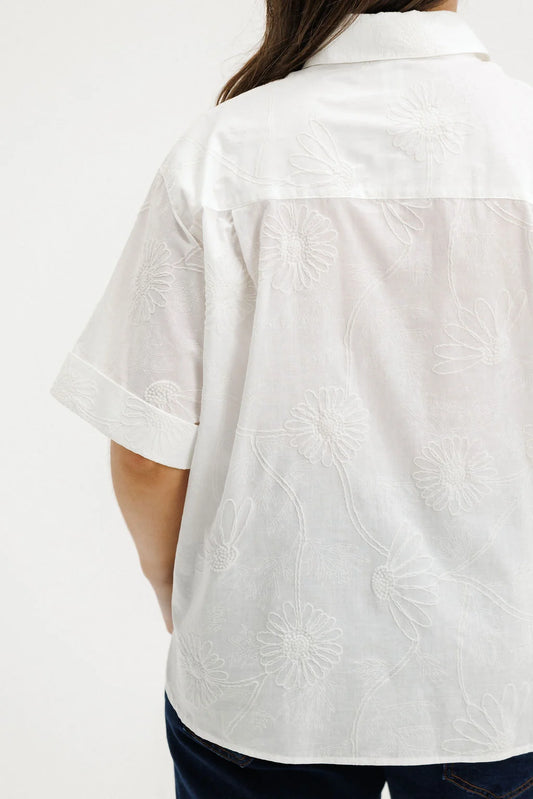 White embroidered shirt worn by a person on a white background