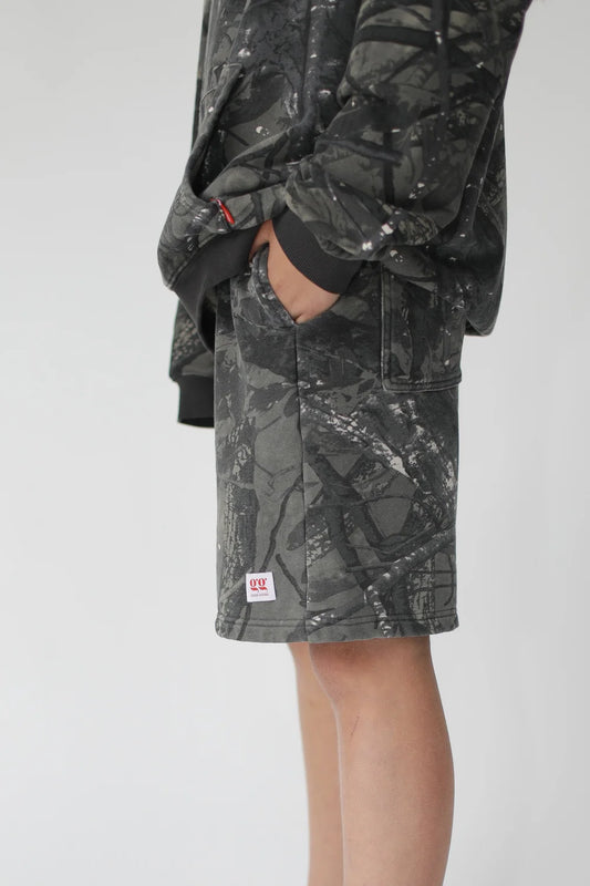 Person wearing camouflage shorts and jacket on a white background