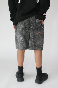 Person wearing camouflage shorts with a black sweatshirt on a white background