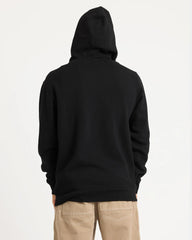 Person wearing a black hoodie and beige pants on a light gray background