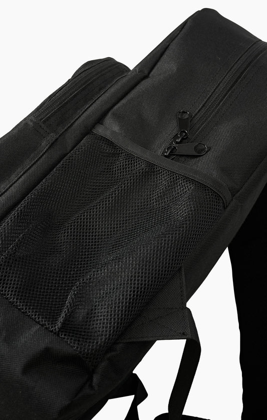 Close-up of a black backpack showing a front zippered pocket with a black zipper pull and a black mesh side pocket, photographed against a plain white background.