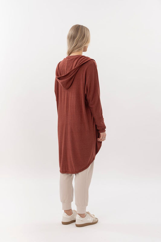 Person wearing a long rust-colored hoodie on a white background