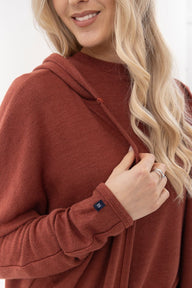 Person wearing a brown hoodie with a close-up of the hood and sleeve.
