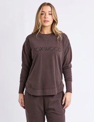 Woman wearing a brown 'FOXWOOD' sweatshirt on a white background