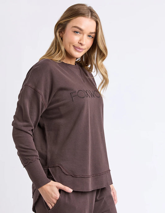 Woman wearing a brown sweatshirt with 'FOXWOOD' branding on a white background