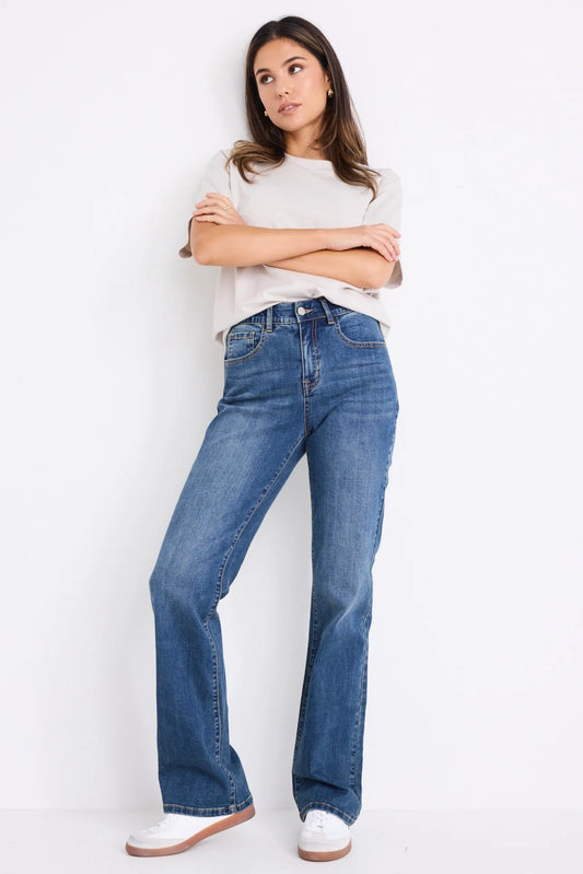 Woman wearing blue jeans and a white shirt against a white background