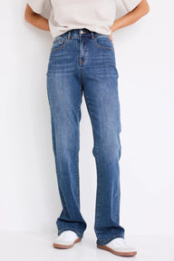 Person wearing blue jeans and white sneakers on a plain background