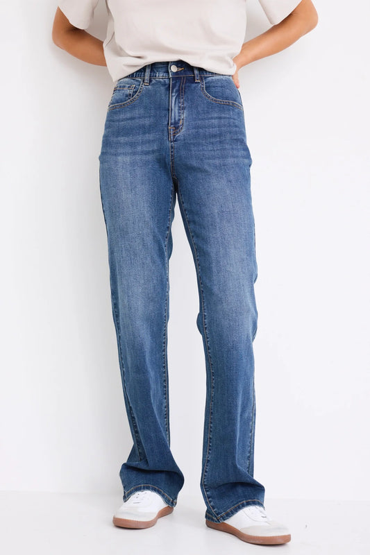 Person wearing blue jeans and white sneakers on a plain background