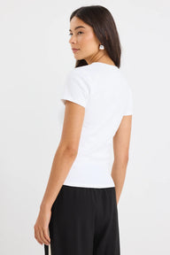 Woman wearing a white t-shirt and black pants on a plain background