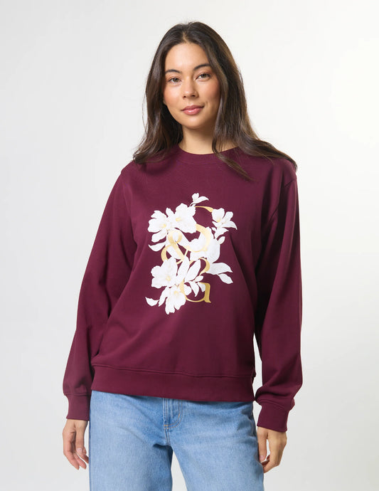Woman wearing a burgundy sweatshirt with a floral design on a white background
