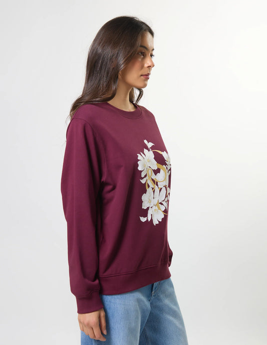 Woman wearing a maroon sweatshirt with floral design on a white background