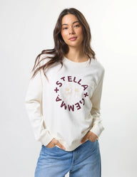 Woman wearing a white sweatshirt with 'Stella + Gemma' text on a plain background