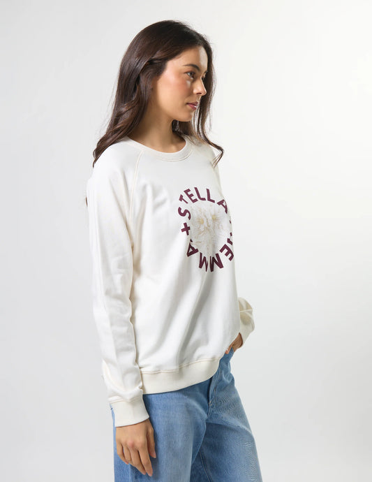 Woman wearing a white sweatshirt with text, standing against a plain background
