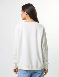 Person wearing a light-colored sweater and blue jeans on a white background
