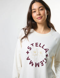 Woman wearing a white sweatshirt with 'Stella + Gemma' logo on a plain background