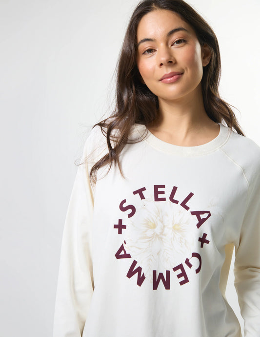 Woman wearing a white sweatshirt with 'Stella + Gemma' logo on a plain background