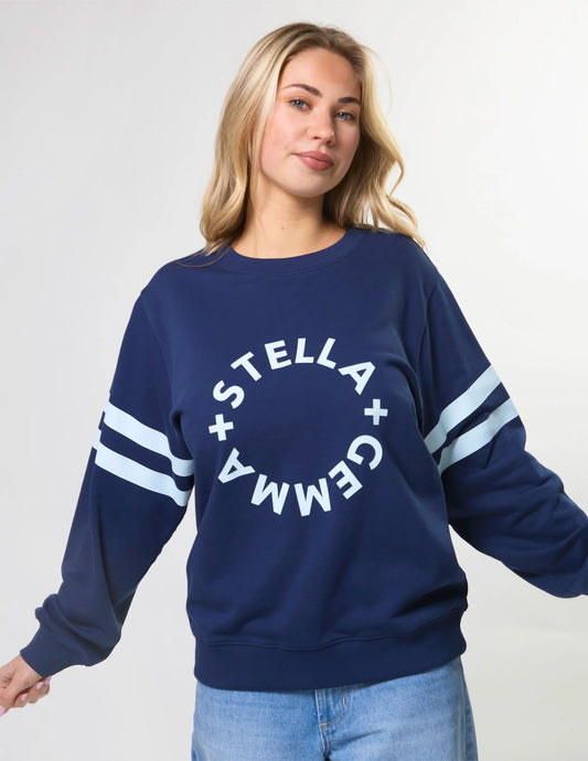 Woman wearing a navy blue sweatshirt with 'Stella + Gemma' logo on a white background