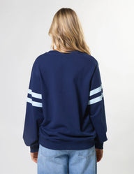 Person wearing a navy blue sweatshirt with white stripes on sleeves against a light gray background