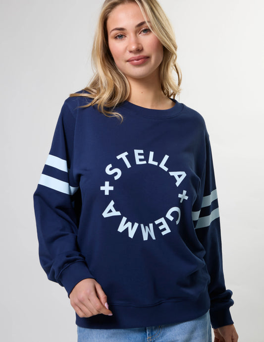 Woman wearing a navy blue sweatshirt with 'Stella + Gemma' logo on a light gray background