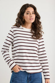 Woman wearing a striped long-sleeve shirt and jeans on a plain background
