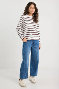 Woman wearing a striped sweater and blue jeans on a white background