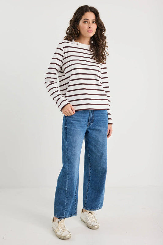 Woman wearing a striped sweater and blue jeans on a white background