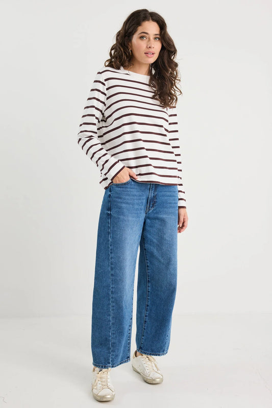 Woman wearing a striped sweater and blue jeans on a white background