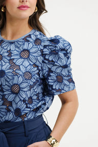 Woman wearing a blue floral blouse with puffed sleeves on a white background