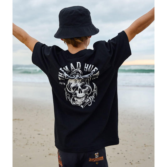 Person wearing a black t-shirt with a skull design and text on a beach