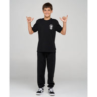 Person wearing a black t-shirt and pants with a logo, standing against a plain background