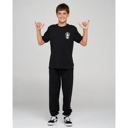 Person wearing a black t-shirt and pants with a logo, standing against a plain background