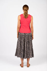 Woman wearing a pink sleeveless top and patterned skirt on a white background