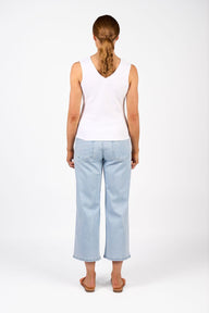 Person wearing a white sleeveless top and light blue jeans on a white background
