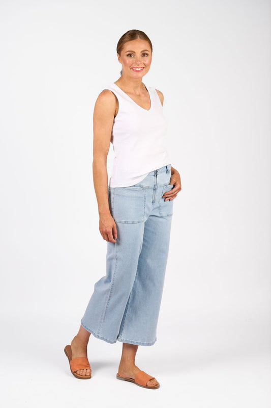 Woman wearing a white sleeveless top and light blue jeans on a white background