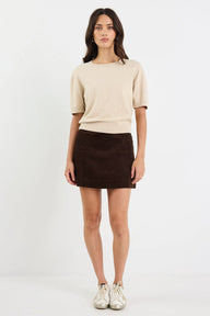 Woman wearing a beige top and brown skirt on a white background