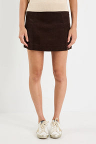 Person wearing a Brown skirt and white sneakers on a plain background