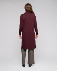 Person wearing a burgundy coat and gray pants on a white background