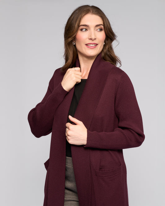 Woman wearing a burgundy cardigan against a gray background
