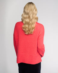 Person wearing a coral sweater with a plain background