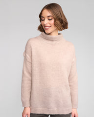 Woman wearing a oat sweater against a plain background