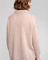 Woman wearing a oat sweater against a gray background