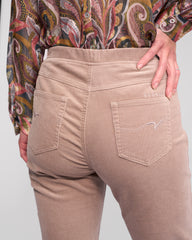 Beige pants worn by a person with a patterned shirt on a plain background
