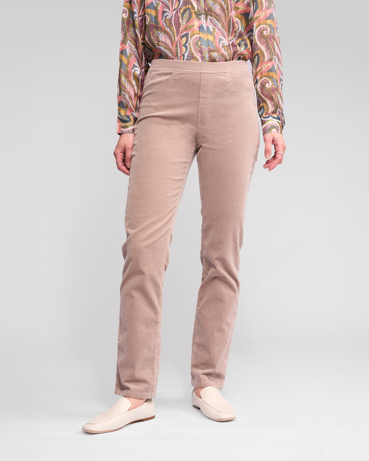 Person wearing beige pants and a patterned top on a plain background