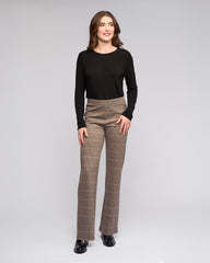 Woman wearing a black top and plaid pants on a gray background