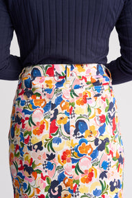 A close-up of a person wearing a colorful floral print skirt with a white waistband and belt, paired with a dark navy ribbed long-sleeve top. The skirt features a busy pattern of flowers and text including 'Sunny Days' and 'Enjoy the Day'.
