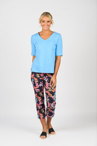Woman wearing Vassalli light blue top and colorful patterned pants on a white background