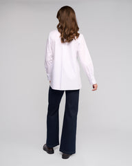 Person wearing a white shirt and dark pants on a plain background