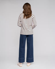 Person wearing a striped shirt and blue jeans on a plain background